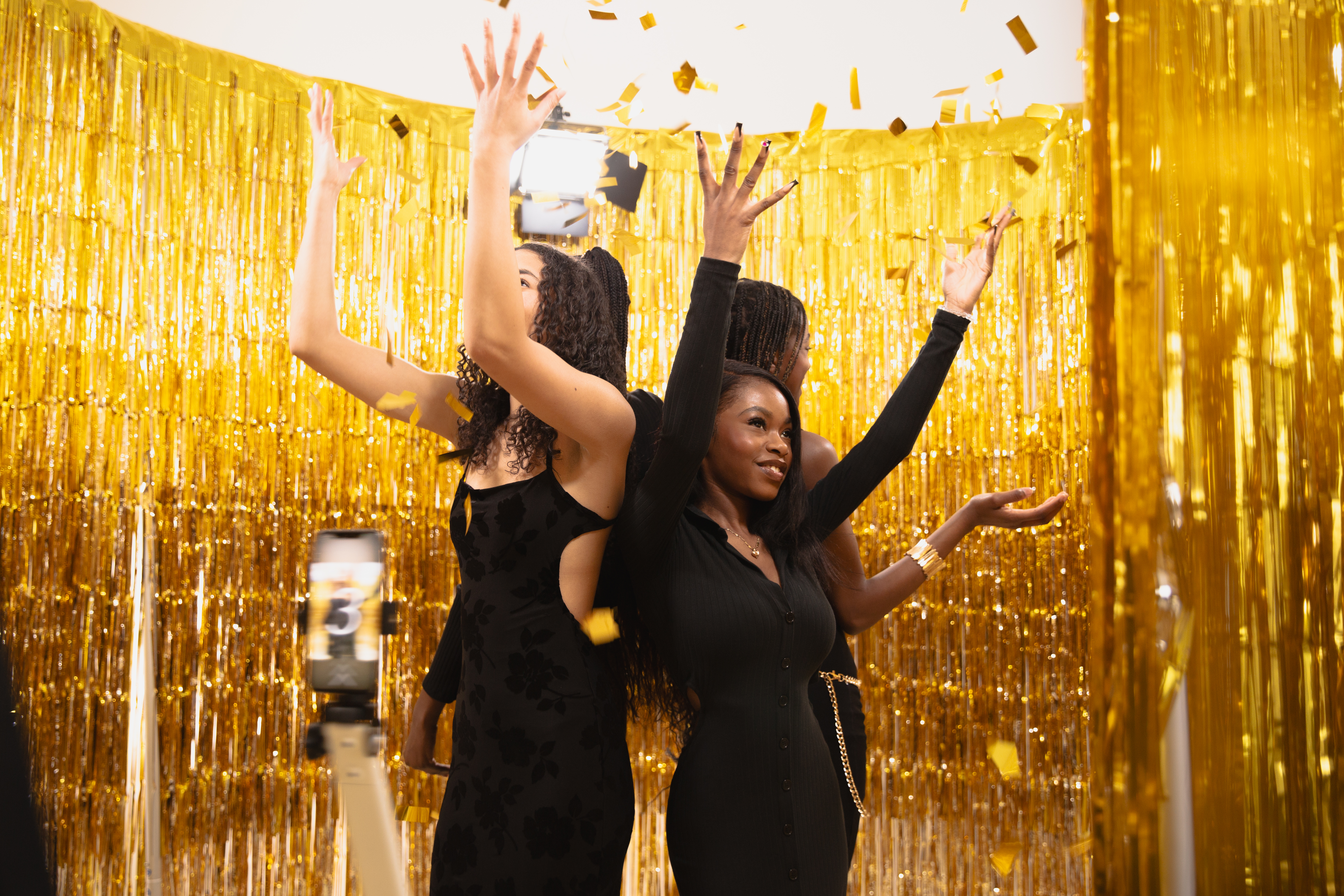 Women with arms raised in gold fringe setup
